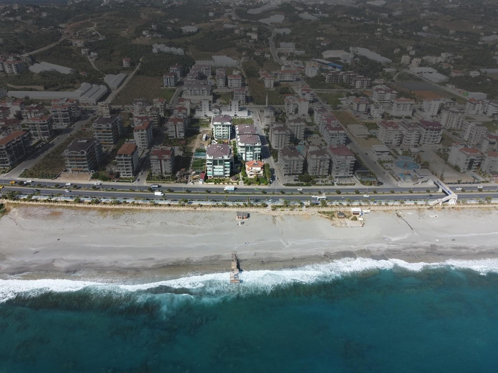 Moda Marine Residence'ın havadan görünümü: sahil yolu, kumsal ve arkada site blokları